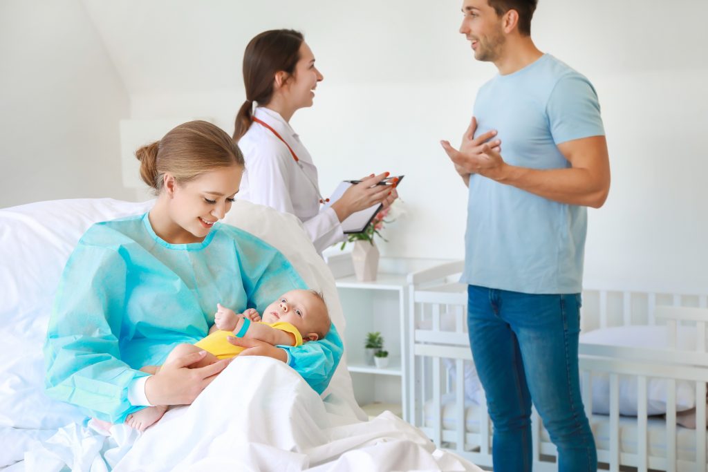 Young woman with newborn baby in maternity hospital