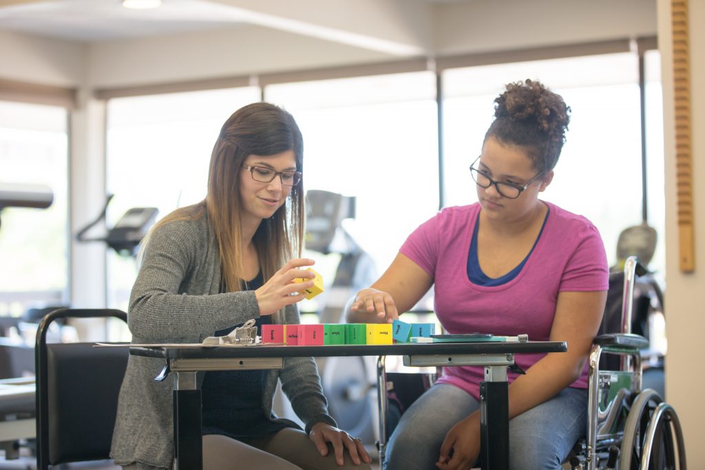 Woman works with teenage girl at rehab clinic