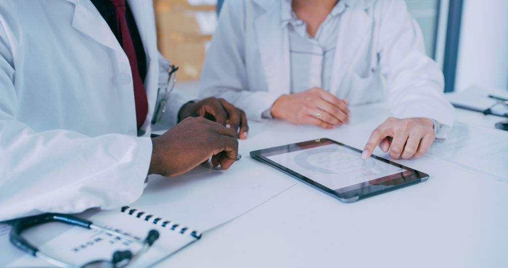 Shot of two doctors using a digital tablet during a discussion in a clinic