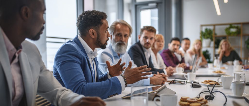 Determined man expressing opinions to a group pf people in a conference room.