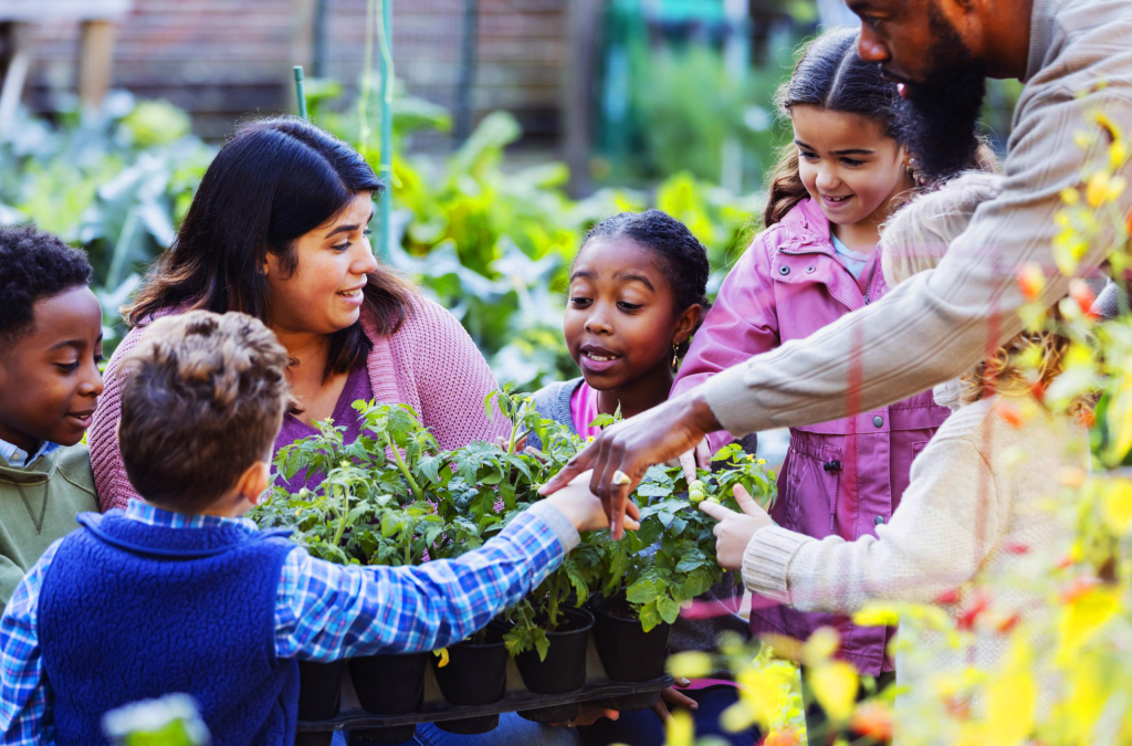 a woman and several children around a garden helping plant