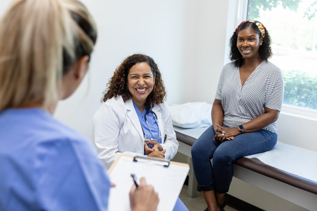 Female doctor and her patient smile while listening to the nurse