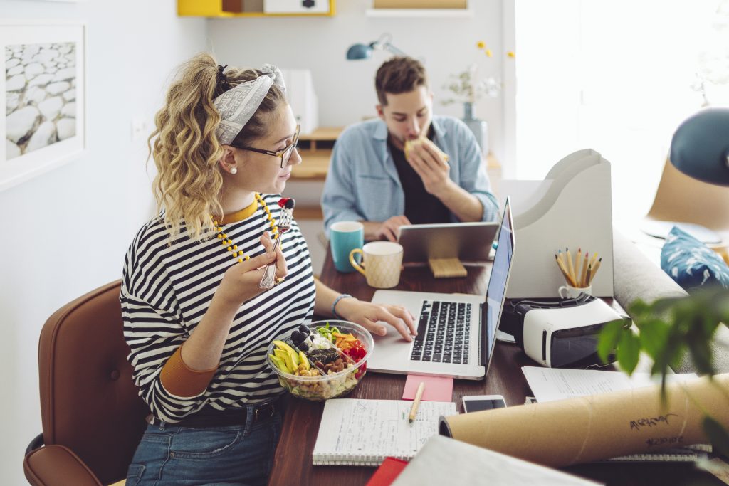 Woman eating healthy and using her laptop