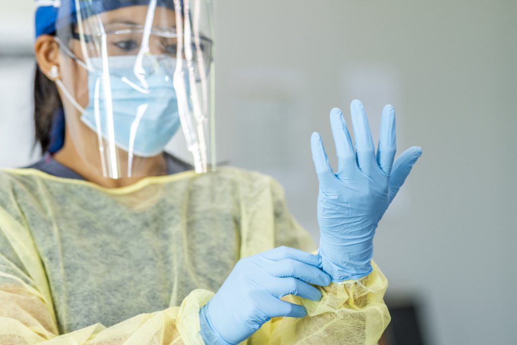 Healthcare worker wearing a face mask, face shield, gown, and gloves. 
