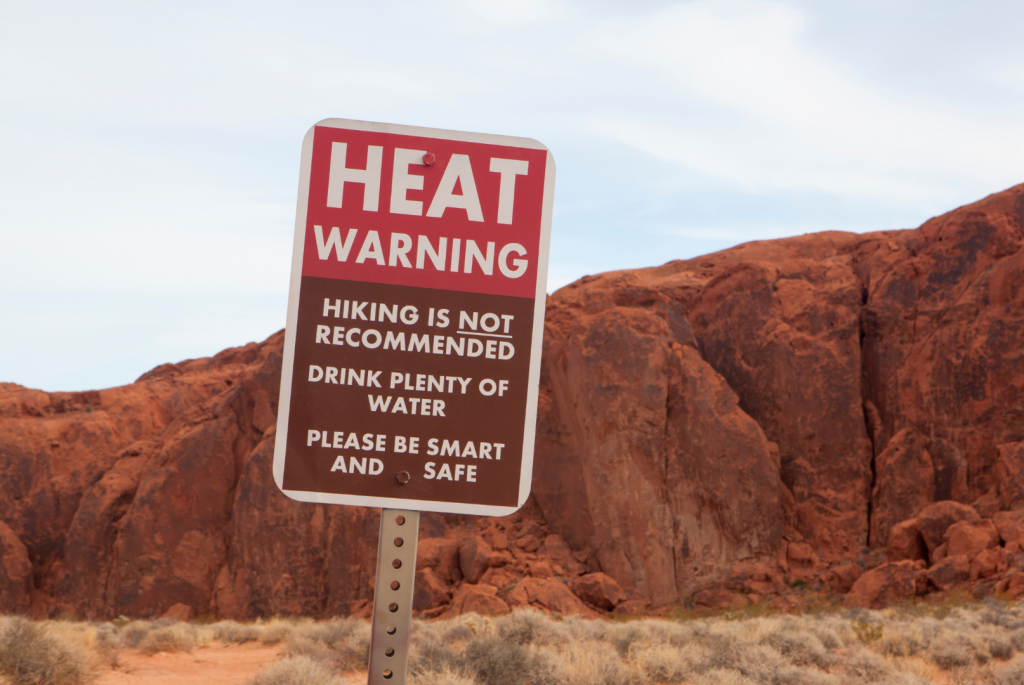 A sign out in the desert warn visitors that it is not safe to hike during high heat.