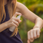 Woman spray her arm with mosquito repellent