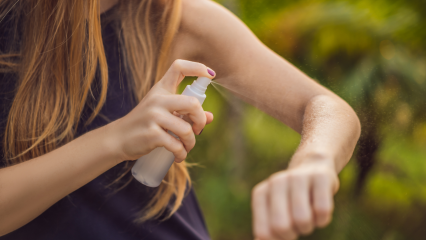 Woman spray her arm with mosquito repellent