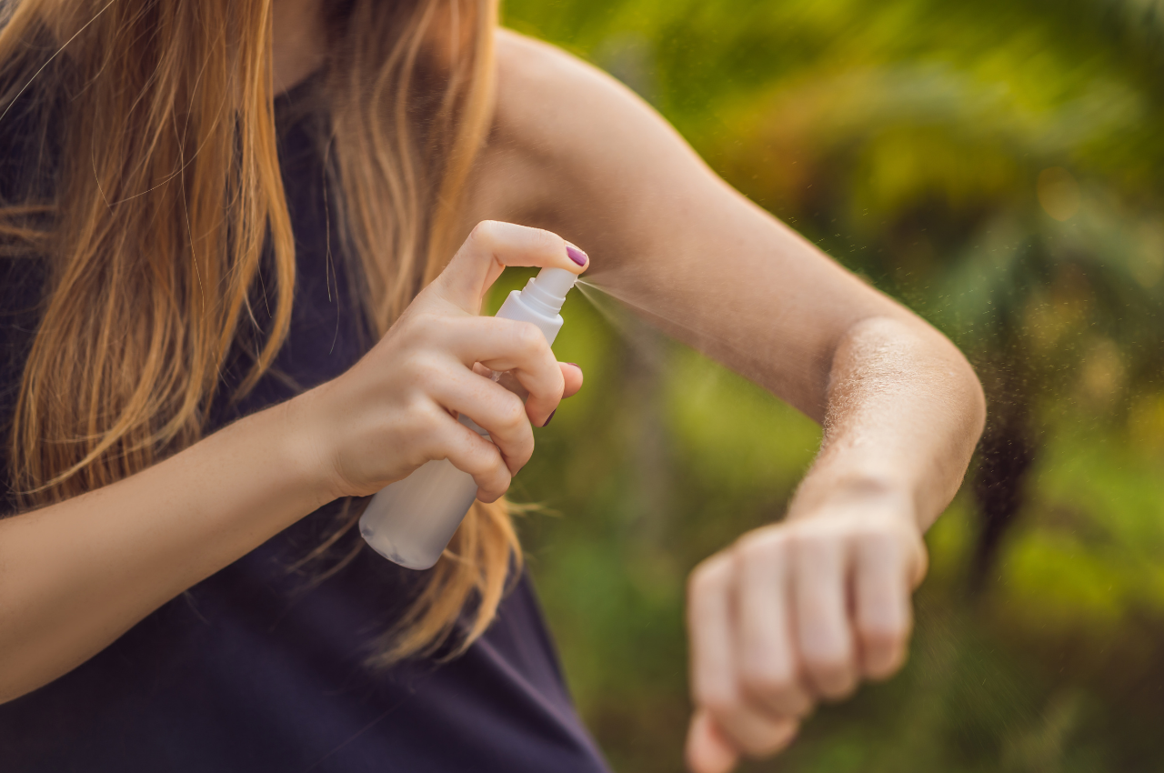 Woman spray her arm with mosquito repellent