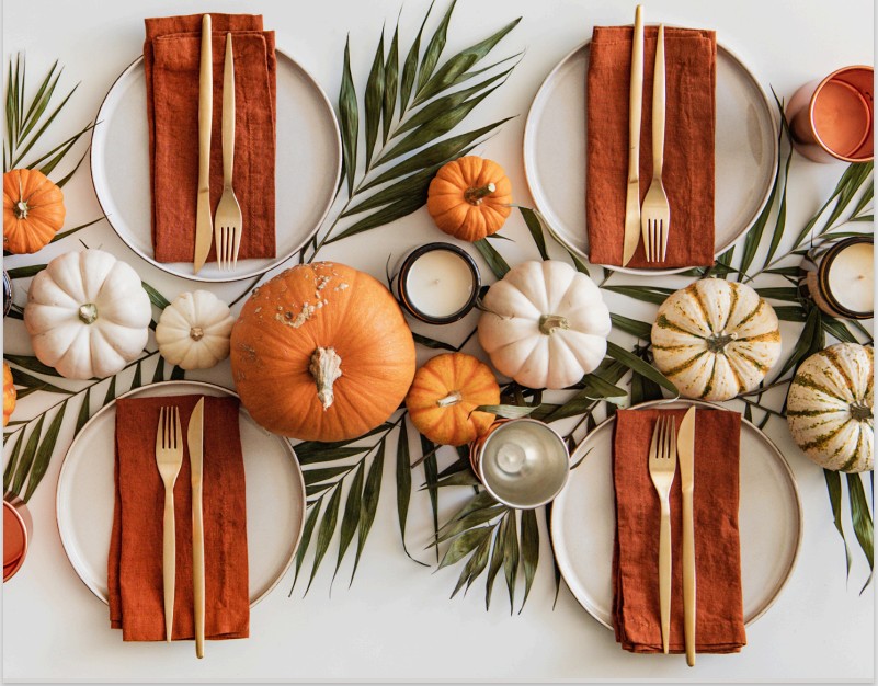 An image of a thanksgiving table with pumpkins and leaves