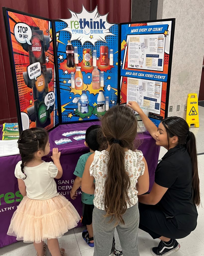 Health educator, Alexis Chaires, teaching kids about healthy beverages using Rethink Your Drink education board at SUN meals event.