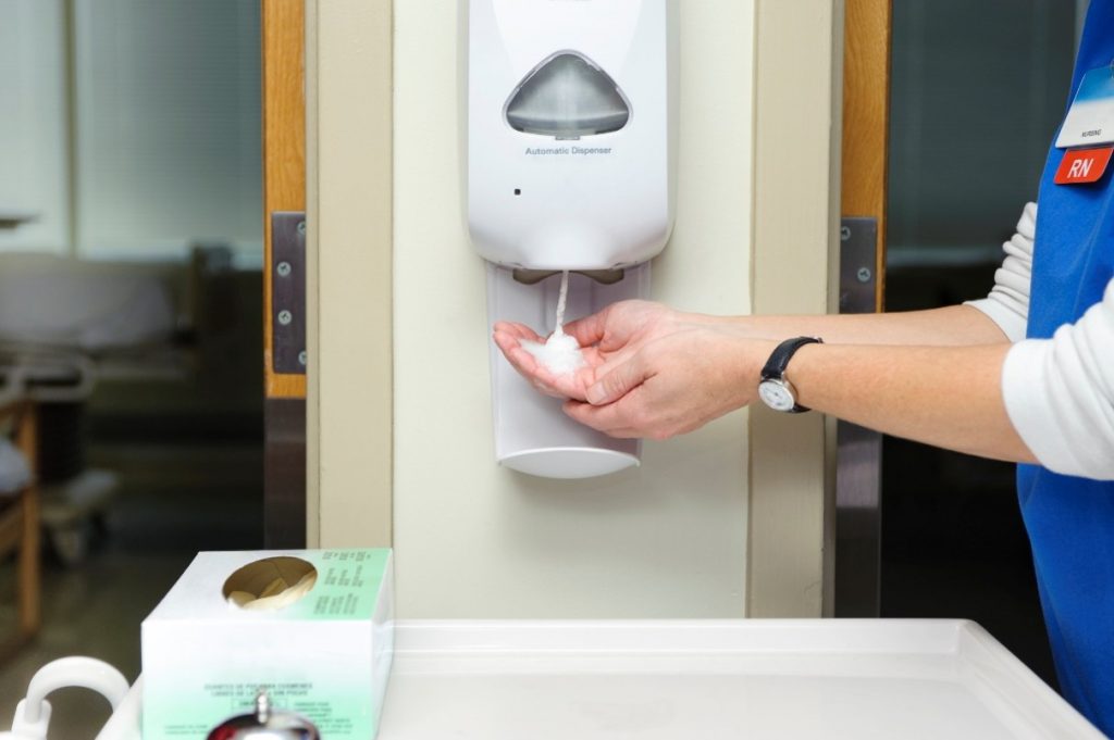 A person is washing their hands by receiving soap from a soap dispenser.