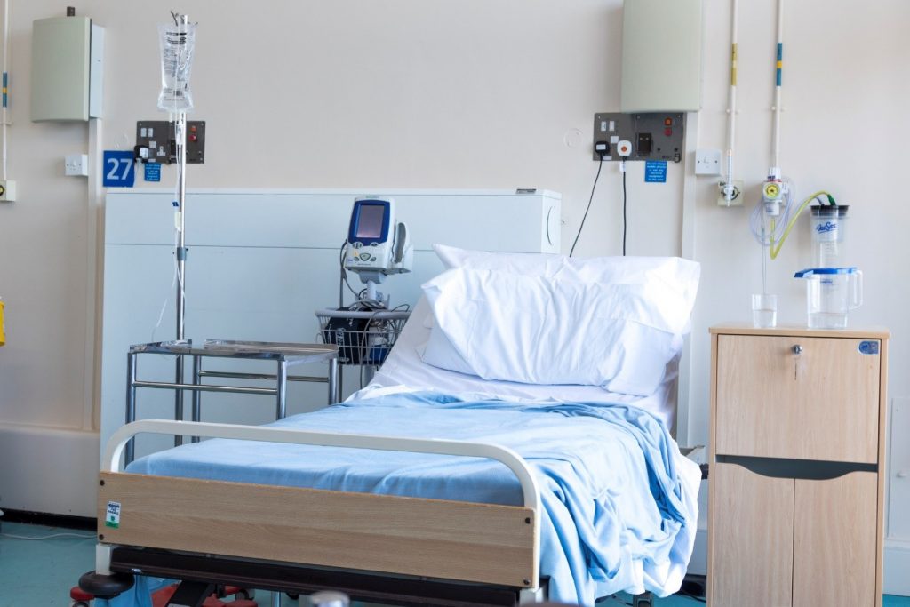 A single hospital bed lies in the center of the room. Various hospital equipment surrounds the bed.